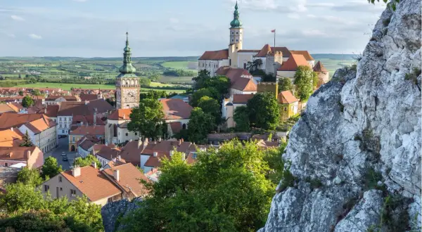 Malerische Stadtansicht von Mikulov, einem der schönsten orte tschechien, mit Schloss und Kirchturm vor grüner Hügellandschaft.