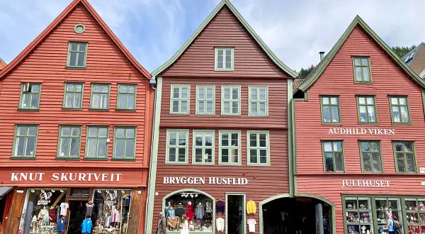 Bunte Holzhäuser in der bergen altstadt, mit Geschäften und Touristen.