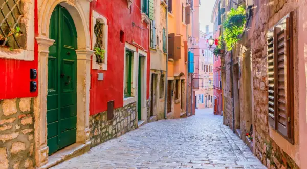 Eine Kopfsteinpflastergasse in Rovinj mit bunten Häusern. Entdecken Sie Rovinj Geheimtipps in dieser malerischen Gasse.
