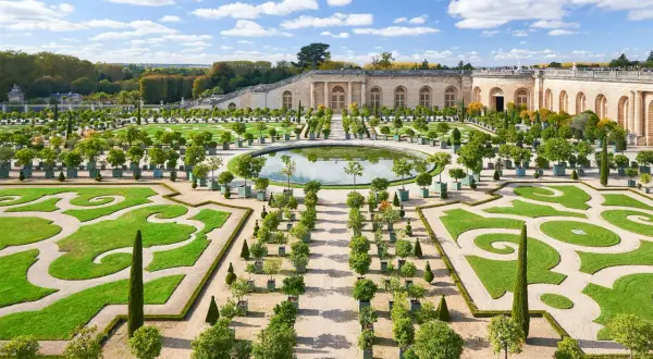 Der Weg von Paris nach Versailles führt durch diesen prächtigen Garten mit symmetrischen Beeten, einem Spiegelteich und dem Schloss im Hintergrund.