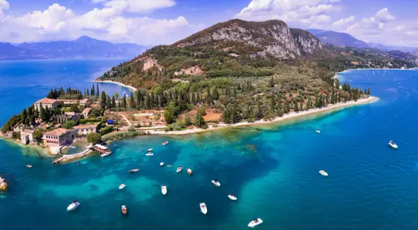 Punta San Vigilio: malerische Halbinsel mit historischen Gebäuden, Olivenhainen und dem türkisfarbenen Gardasee, belebt durch zahlreiche Boote.