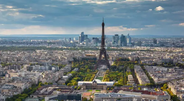 Paris in 2 Tagen: Eiffelturm ragt über die Stadt, umgeben von grünen Parks und Haussmann-Gebäuden. Im Hintergrund moderne Hochhäuser.