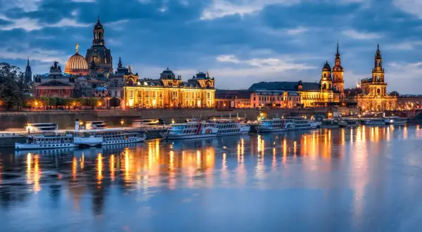Dresden bei Nacht: beleuchtete Frauenkirche und Zwinger spiegeln sich im Wasser. Perfekte Reiseziele im November in Deutschland.
