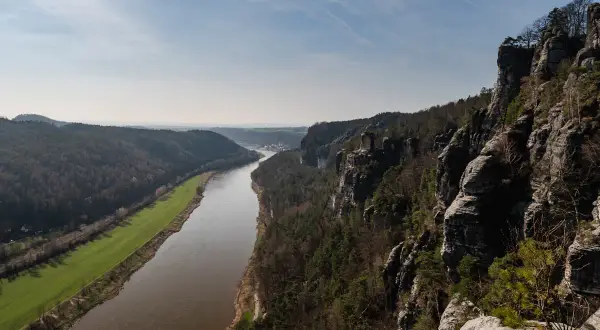 Blick von den Felsen auf die Elbe und die umliegenden Wälder. Eine perfekte Kulisse für eine **Rauenstein Wanderung**.