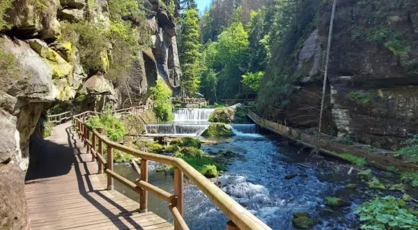 Holzstege schlängeln sich durch eine Schlucht mit Kaskaden. Ein perfekter Ort zum Hrensko wandern.
