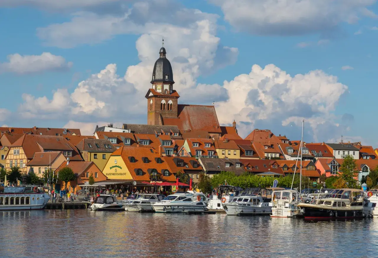 Hafen mit vielen Booten und einem Restaurant, hinter dem sich eine Stadt mit Kirchturm und roten Dächern erstreckt. Perfekte ausflugsziele waren.