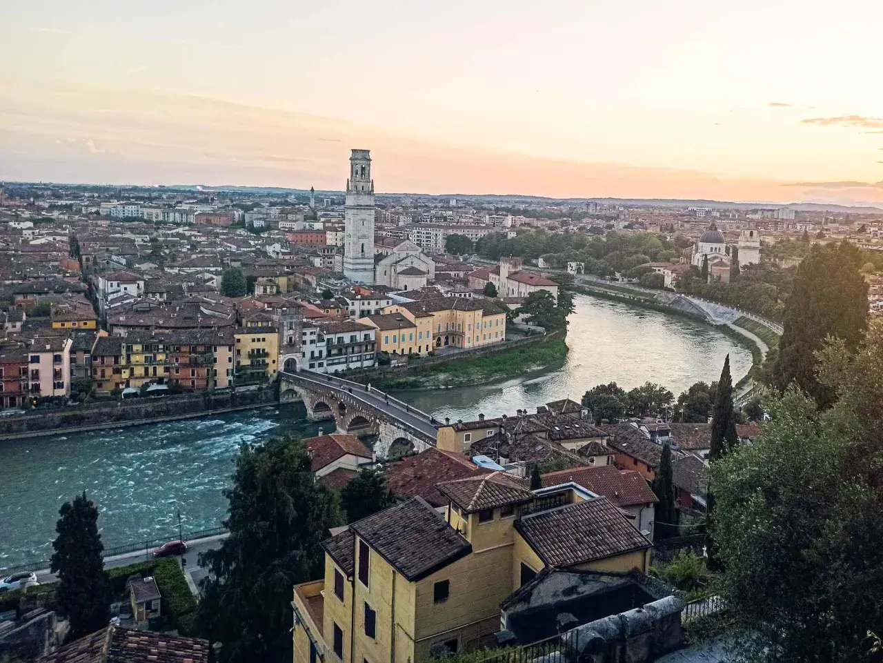 Sonnenuntergang über Verona: malerischer Blick auf die Etsch, die Ponte Pietra und den Torre dei Lamberti. Ein perfekter Ort für Sightseeing in Verona.
