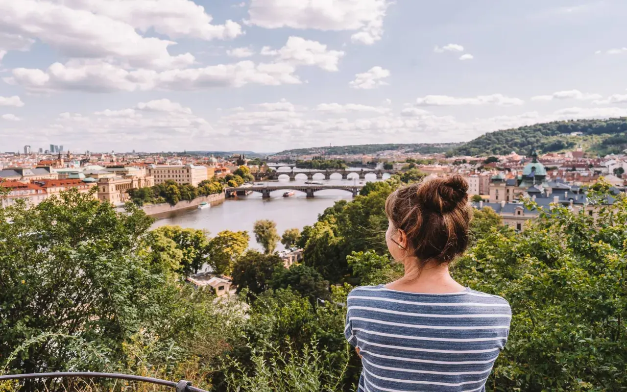 Frau genießt den Sommerblick auf Prag mit der Moldau und Brücken.