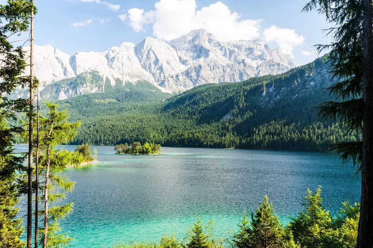 Türkisblaue See mit Inseln, umgeben von dichten Wäldern und majestätischen Bergen. Ein wahres Naturwunder Deutschlands.