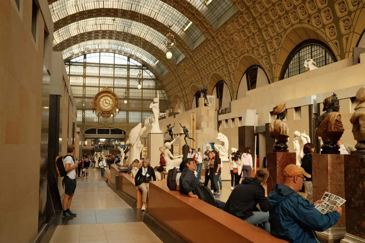 Besucher bestaunen Skulpturen und die große Uhr im **Museum** d'Orsay.