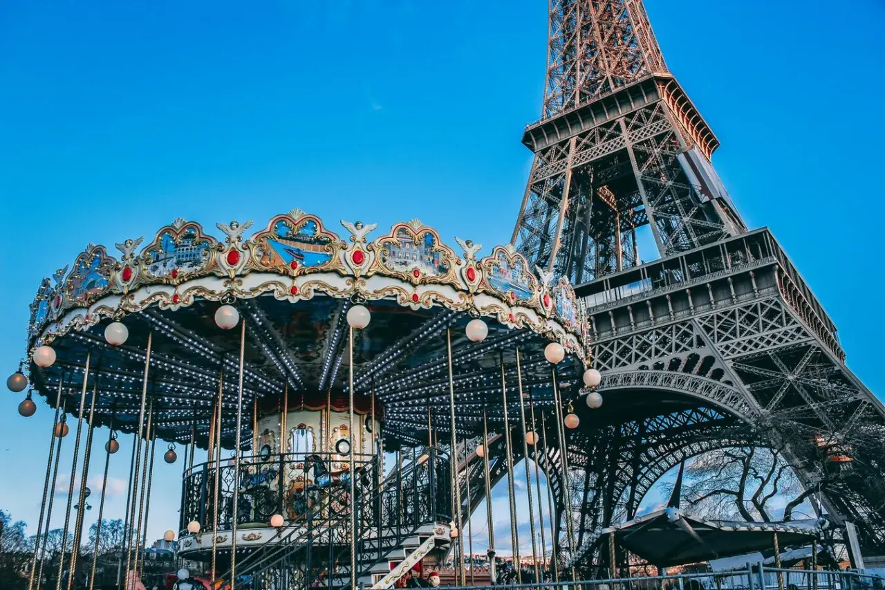 Ein festlich beleuchteter Karussell dreht sich vor dem Eiffelturm am Trocadéro in Paris.