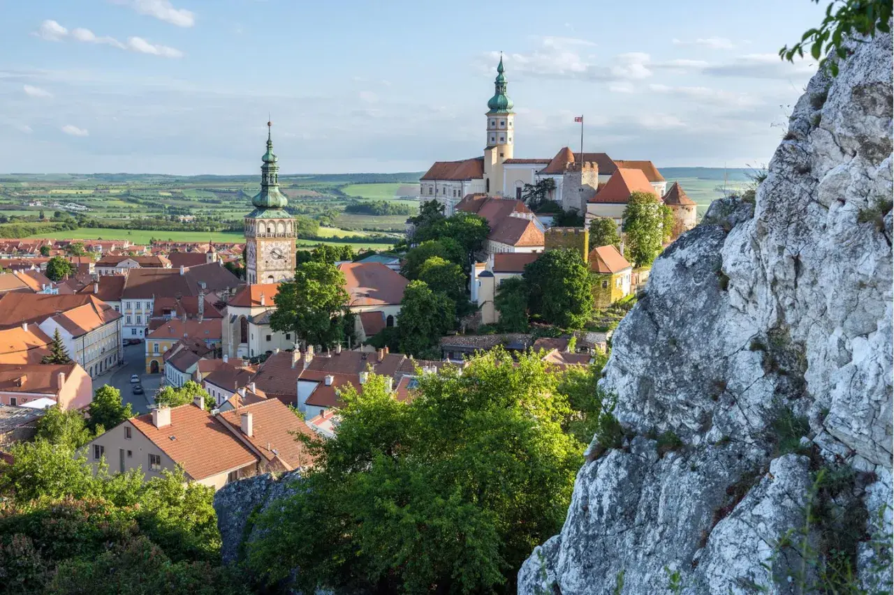 Malerische Stadtansicht von Mikulov, einem der schönsten orte tschechien, mit Schloss und Kirchturm vor grüner Hügellandschaft.