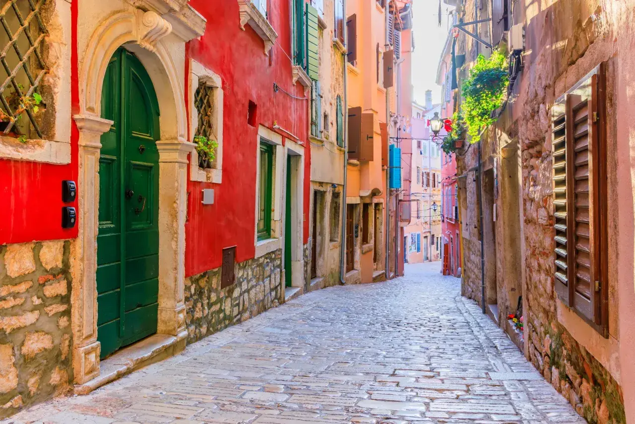 Eine Kopfsteinpflastergasse in Rovinj mit bunten Häusern. Entdecken Sie Rovinj Geheimtipps in dieser malerischen Gasse.