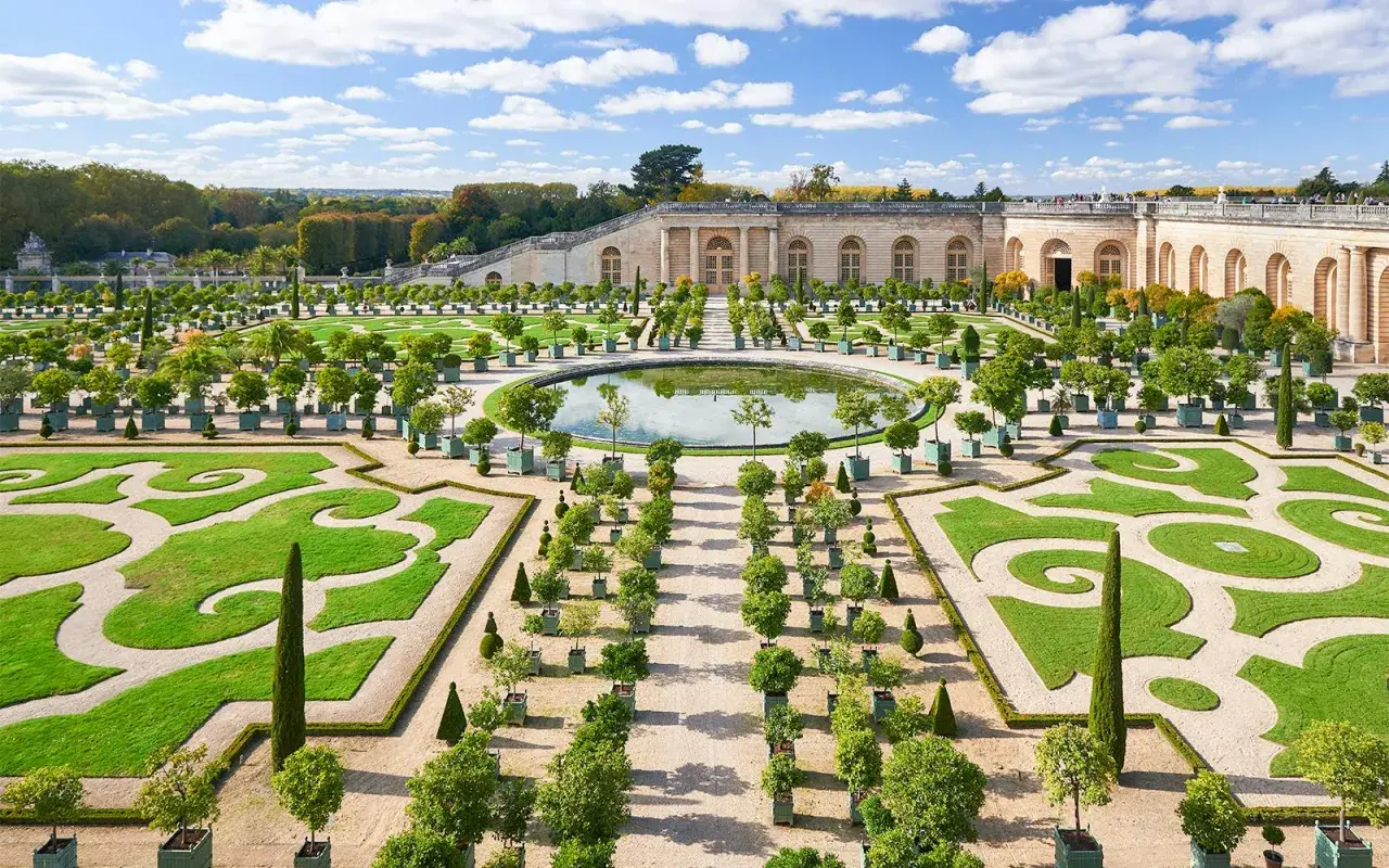 Der Weg von Paris nach Versailles führt durch diesen prächtigen Garten mit symmetrischen Beeten, einem Spiegelteich und dem Schloss im Hintergrund.
