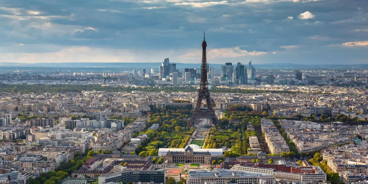 Paris in 2 Tagen: Eiffelturm ragt über die Stadt, umgeben von grünen Parks und Haussmann-Gebäuden. Im Hintergrund moderne Hochhäuser.
