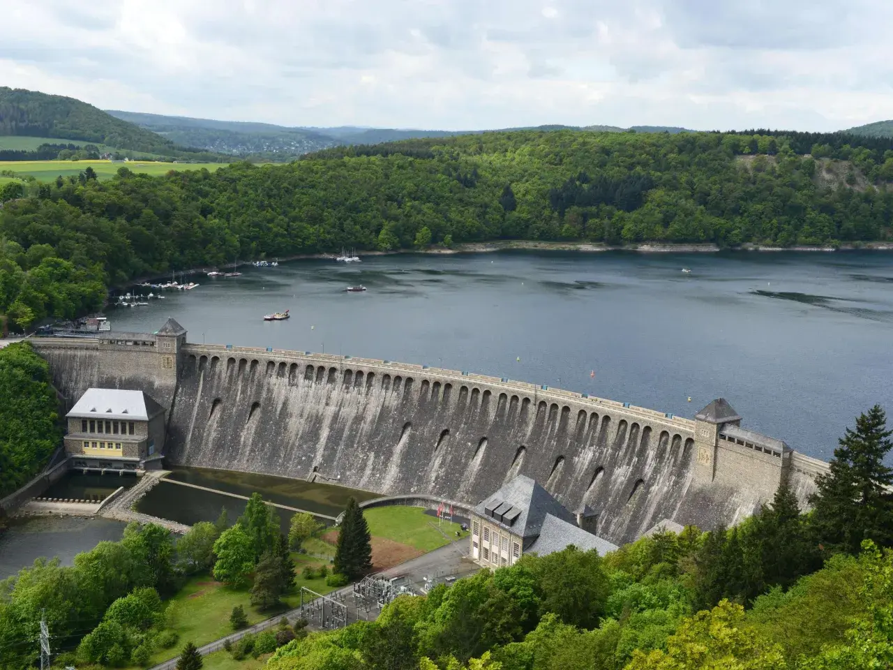 Stausee mit imposanter Staumauer, umgeben von grünen Wäldern. Ein tolles Ziel für Ausflugsziele Hessen, mit Booten auf dem Wasser.