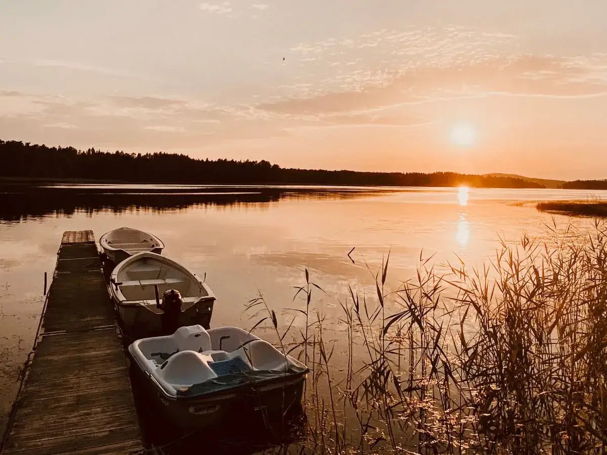 Boote am Steg im Abendlicht, ein malerisches Bild der schwedischen Landschaft. Highlights der Natur spiegeln sich im ruhigen Wasser.