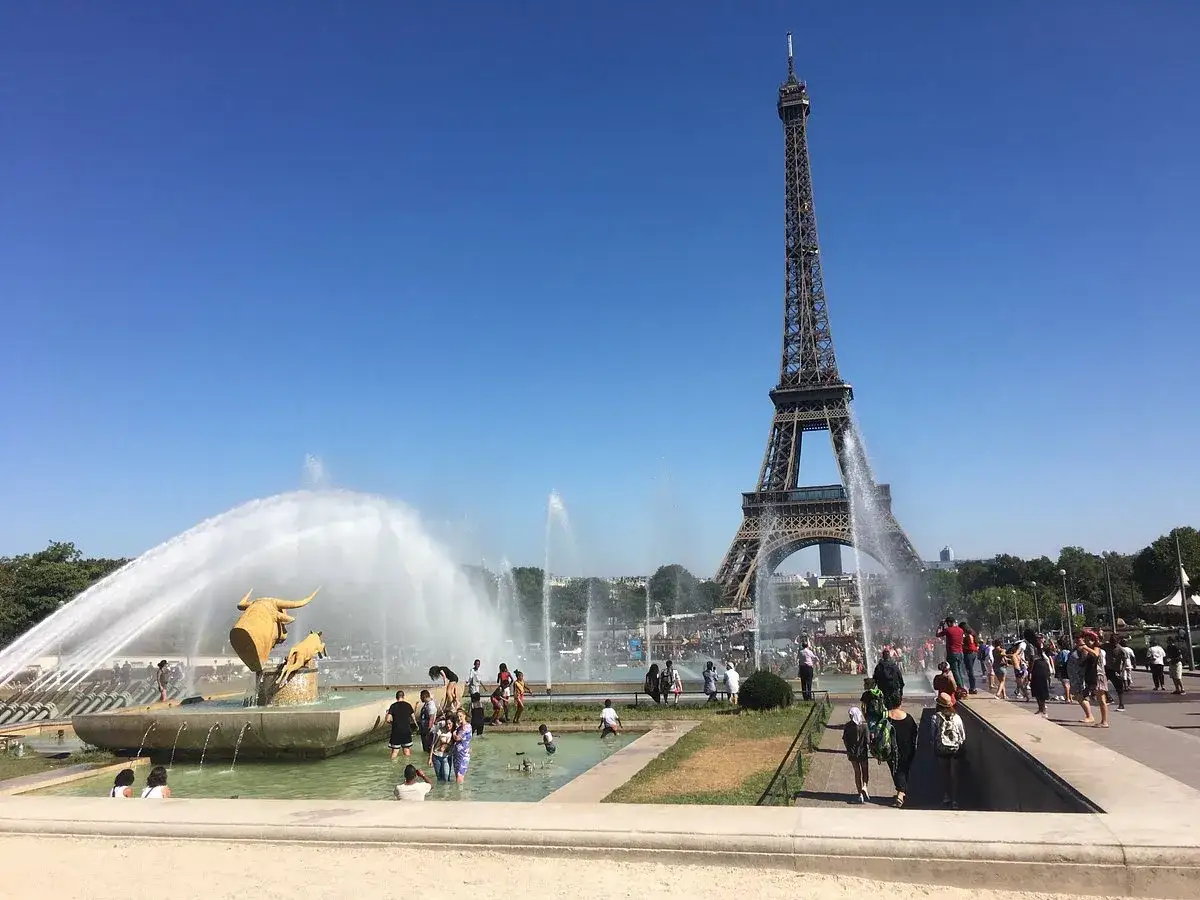 Eiffelturm und Wasserspiele am Trocad&eacute;ro Paris. Menschen genie&szlig;en die Sonne und die Font&auml;nen.