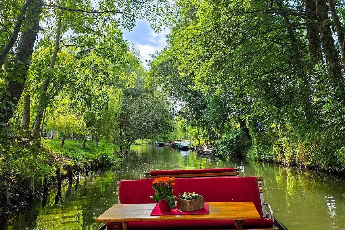 Idyllischer Spreewald Tagesausflug per Kahn. Grüne Ufer, ruhiges Wasser und rote Sitzbänke laden zur Entspannung ein.