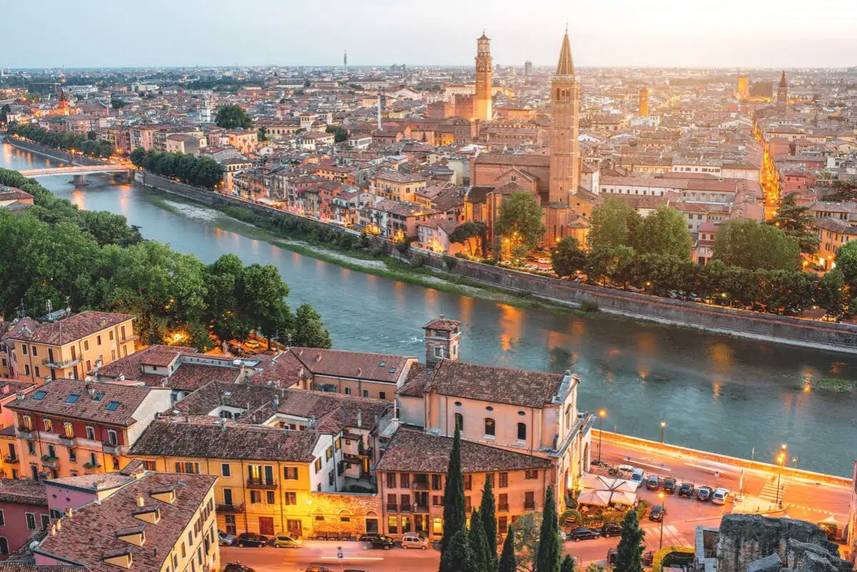 Verona bei Sonnenuntergang: malerische Altstadt mit dem Fluss Etsch, Kircht&uuml;rmen und beleuchteten H&auml;usern &ndash; ein perfekter Ort f&uuml;r Sightseeing in Verona.