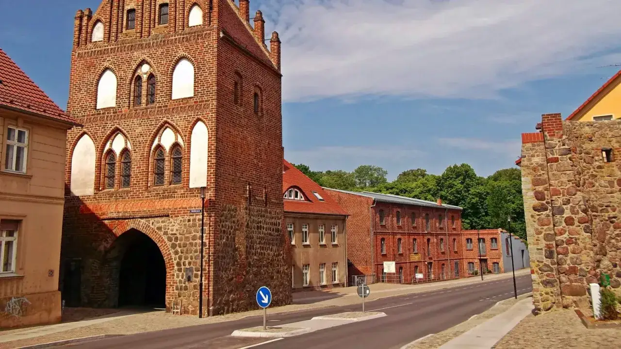 Historisches Stadttor in Templin Altstadt, mit Backstein und Feldsteinmauern, daneben rote Backsteingebäude und grüne Bäume.