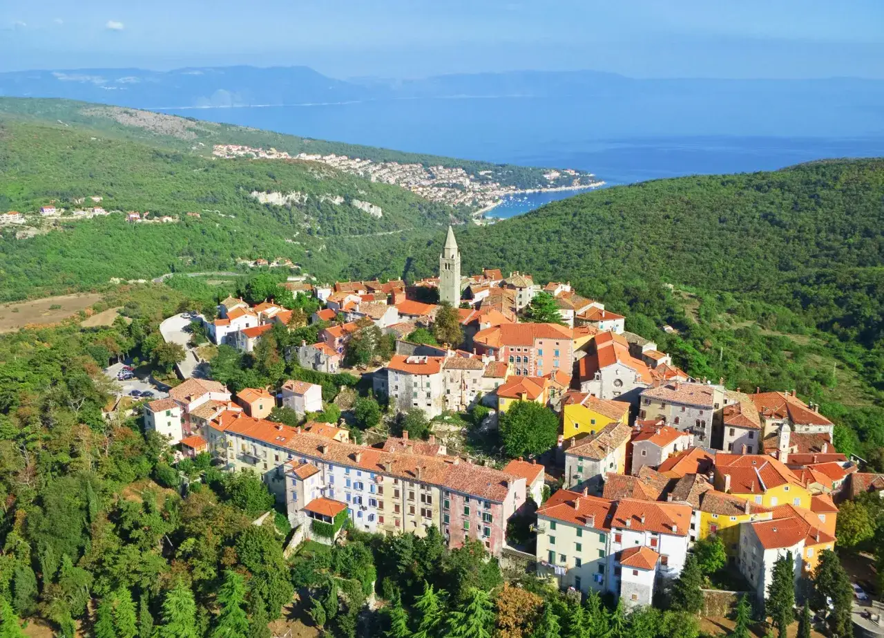 Blick auf ein malerisches Dorf auf einem H&uuml;gel in Istrien, ein echter Geheimtipp mit roten D&auml;chern und Blick aufs Meer.