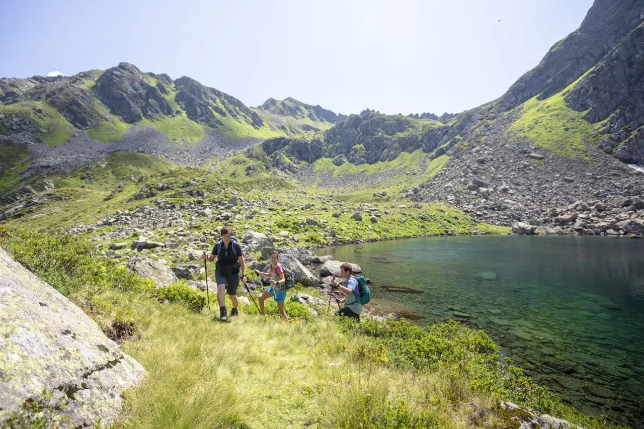 Drei Wanderer genießen die atemberaubende Berglandschaft und den klaren Bergsee beim St. Gallenkirch wandern.