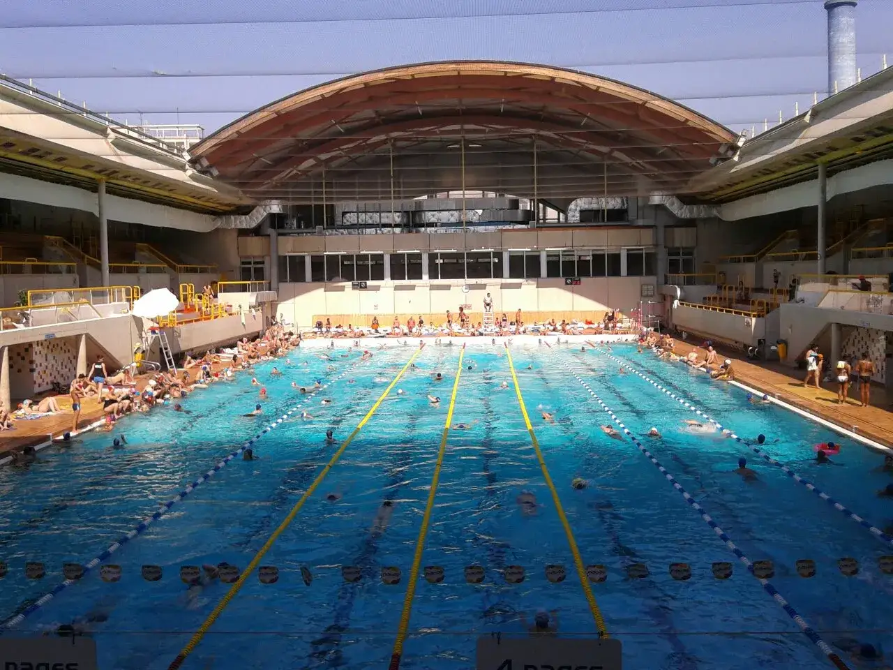 Gro&szlig;es Schwimmbad mit vielen Menschen, die schwimmen und sich sonnen. Ein perfekter Tag zum Schwimmen in Paris.