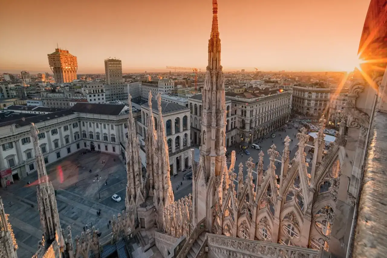 Sonnenuntergang &uuml;ber Mailand. Die filigranen Spitzen des Doms ragen in den orangefarbenen Himmel. Ein perfekter Ausblick f&uuml;r einen 3-Tage-Trip nach Mailand.