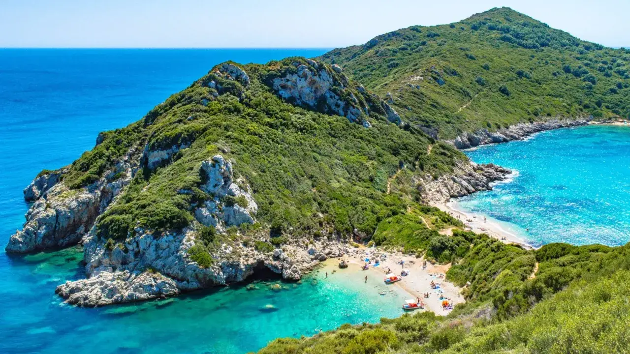 Grüne Hügel treffen auf türkisfarbenes Meer. Ein versteckter Strand mit wenigen Menschen – ein echter Geheimtipp für Griechenland.