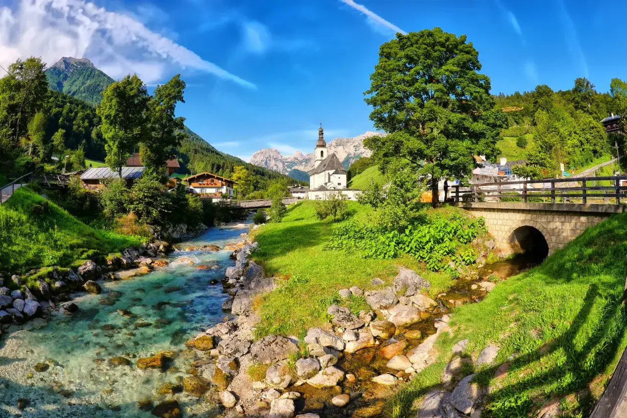 Alpenpanorama mit Kirche, Berg und klarem Bach &ndash; perfekte Kulisse f&uuml;r Mikroabenteuer Ideen.