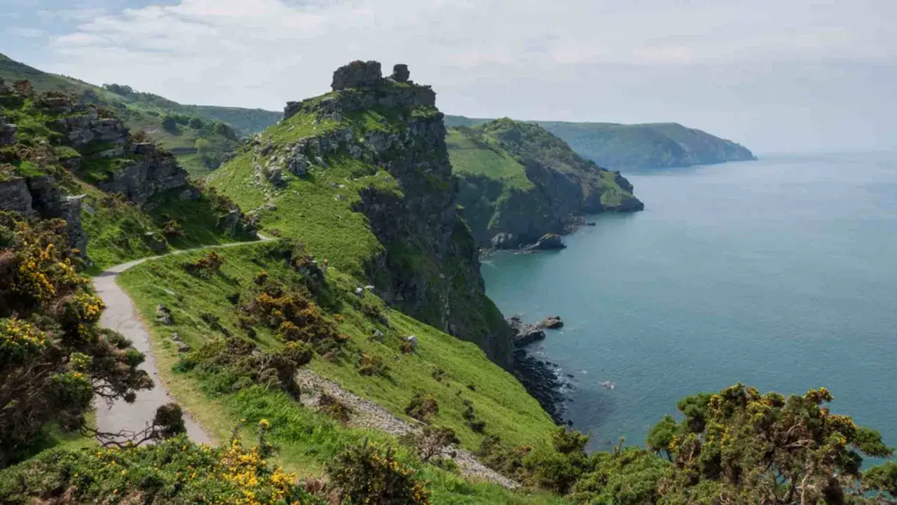 Gr&uuml;ner K&uuml;stenpfad mit Felsen und Meer. Der South West Coast Path ist ein langer Weg, der hier durch eine dramatische Landschaft f&uuml;hrt.