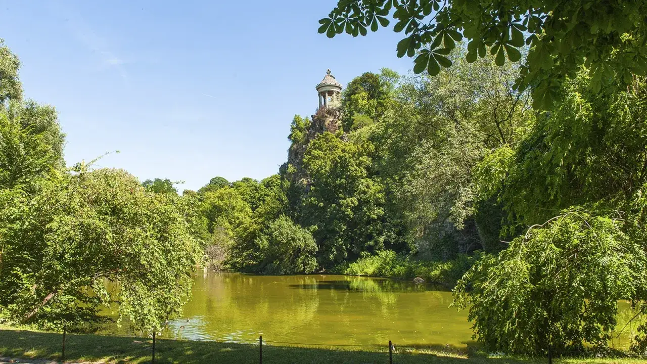 Idyllischer See im Parc des Buttes Chaumont mit einem Tempel auf einem Felsen.