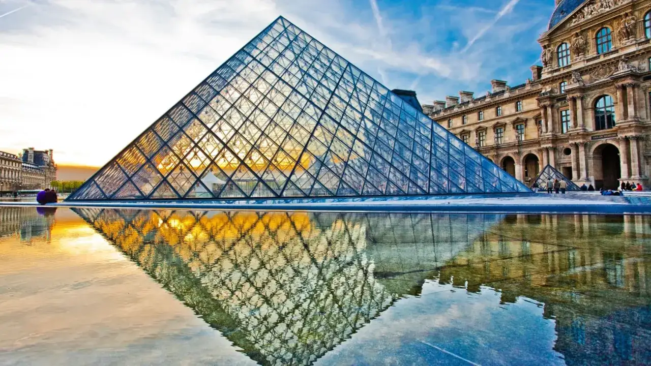 Glaspyramide des Louvre spiegelt sich im Wasser. Ein perfekter Moment für Sightseeing in Paris.