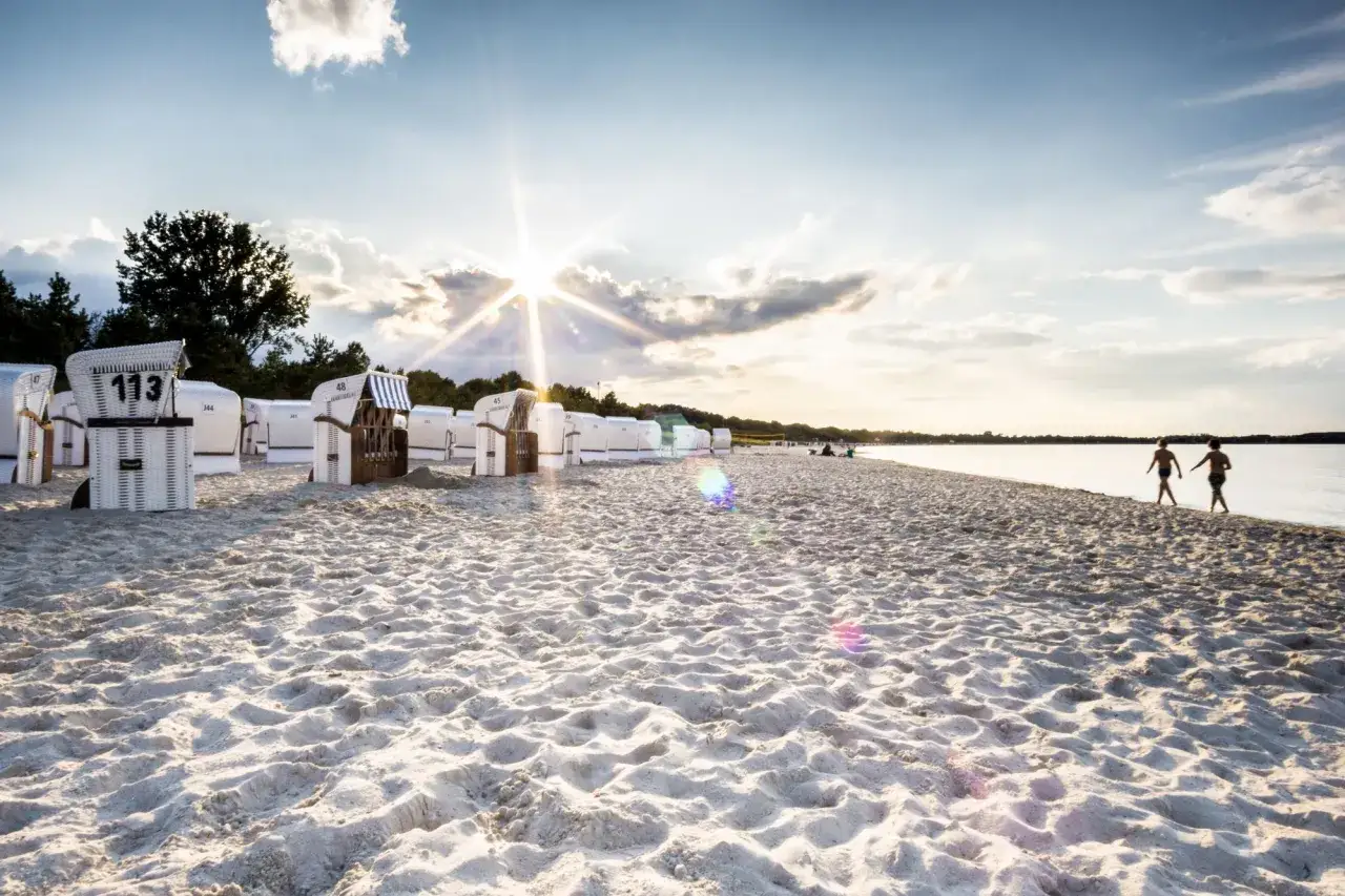Strandkörbe am Ostseestrand von Boltenhagen, zwei Kinder laufen am Wasser entlang. Hier finden Sie die besten Geheimtipps für Ihren Urlaub.