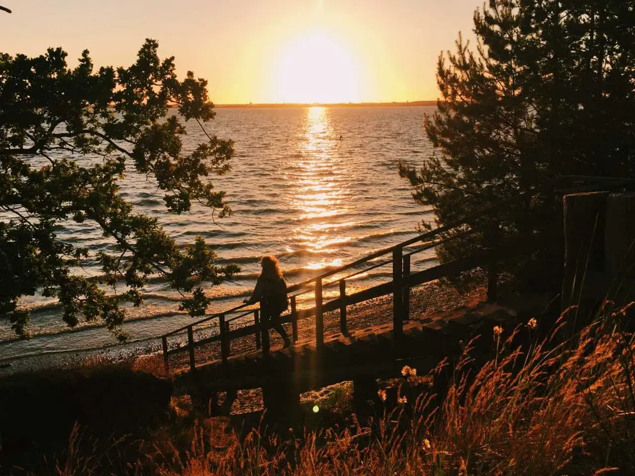 Sonnenuntergang am Meer, eine Frau steigt eine Holztreppe hinab. Insidertipps Usedom f&uuml;r magische Momente.