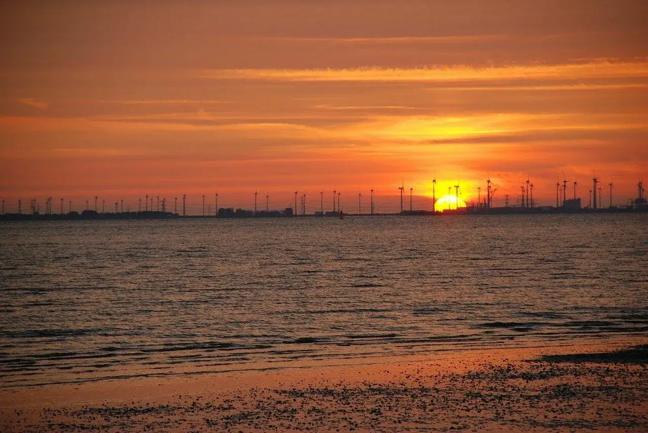 Sonnenuntergang am Emden Strand mit Windr&auml;dern und Industrie im Hintergrund.