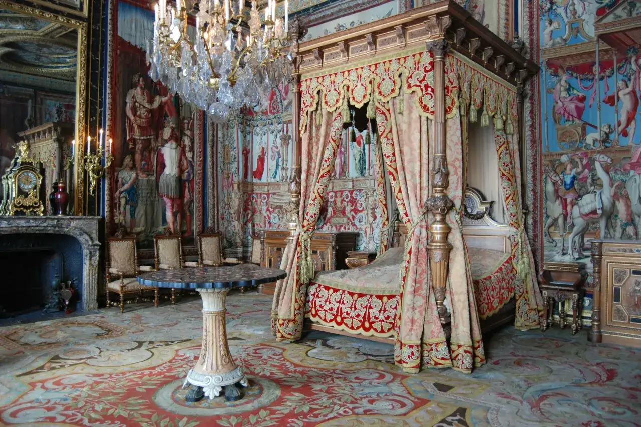Prunkvolles Schlafzimmer im Schloss Fontainebleau mit Himmelbett, Wandteppichen und Kronleuchter.