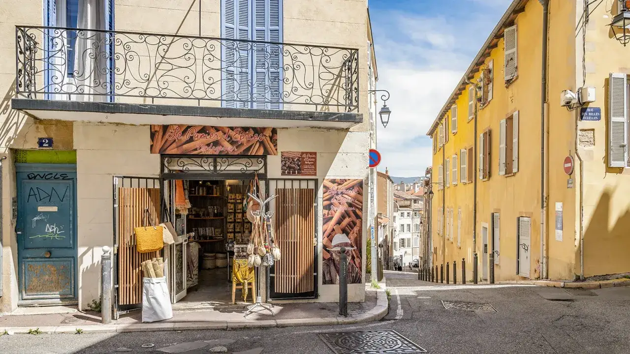 Bunte Häuserfassaden und ein Gewürzladen in der Marseille Altstadt. Eine charmante Gasse mit mediterranem Flair.