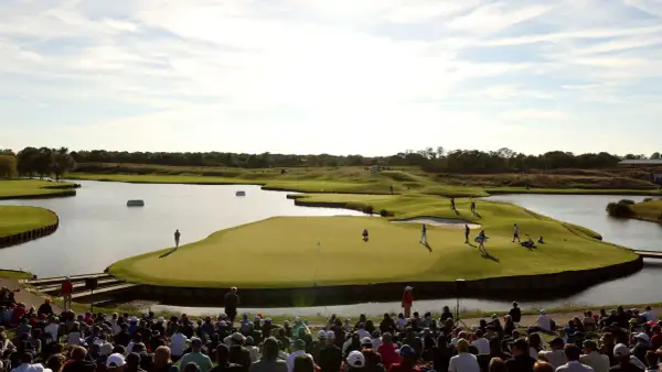 Golfer auf dem Grün am Le Golf National, umgeben von Wasser und Zuschauern.