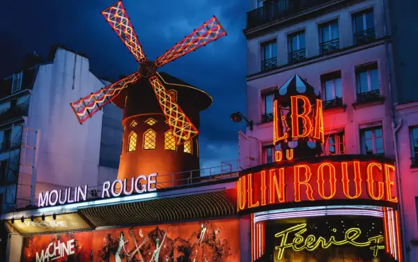 Das Moulin Rouge in Paris bei Nacht. Ein ikonisches Wahrzeichen mit leuchtenden Neonschildern und dem berühmten roten Windrad.