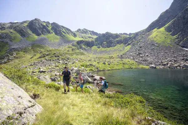 Drei Wanderer genießen die atemberaubende Berglandschaft und den klaren Bergsee beim St. Gallenkirch wandern.
