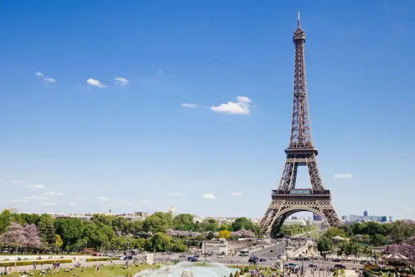 Eiffelturm, ein Paris must see, ragt in den blauen Himmel. Menschen genießen den sonnigen Tag im Park.